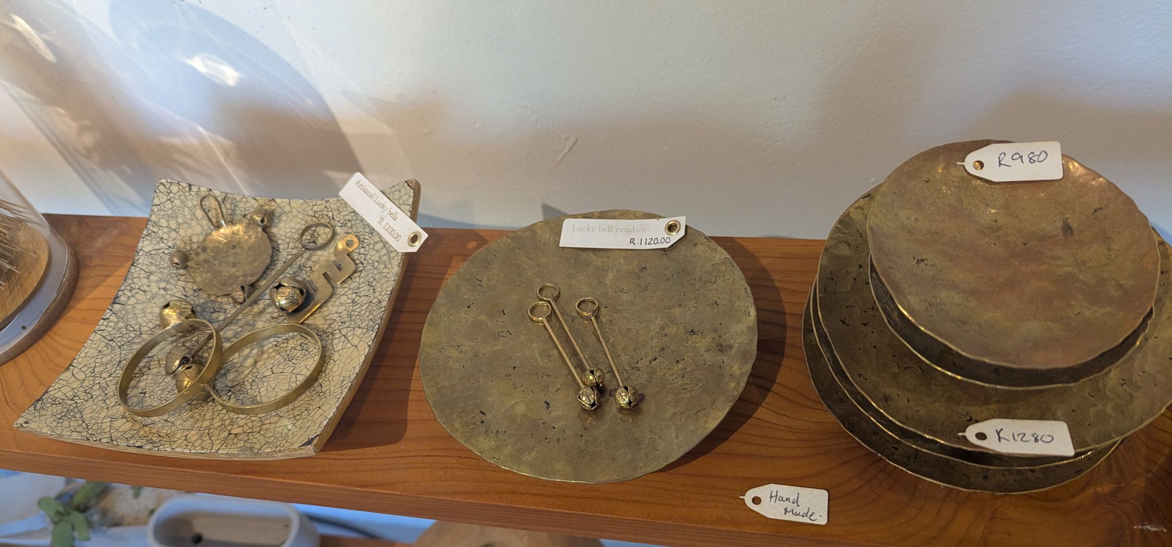 Lucky bell pieces and hammered brass plates on a yellowwood shelf