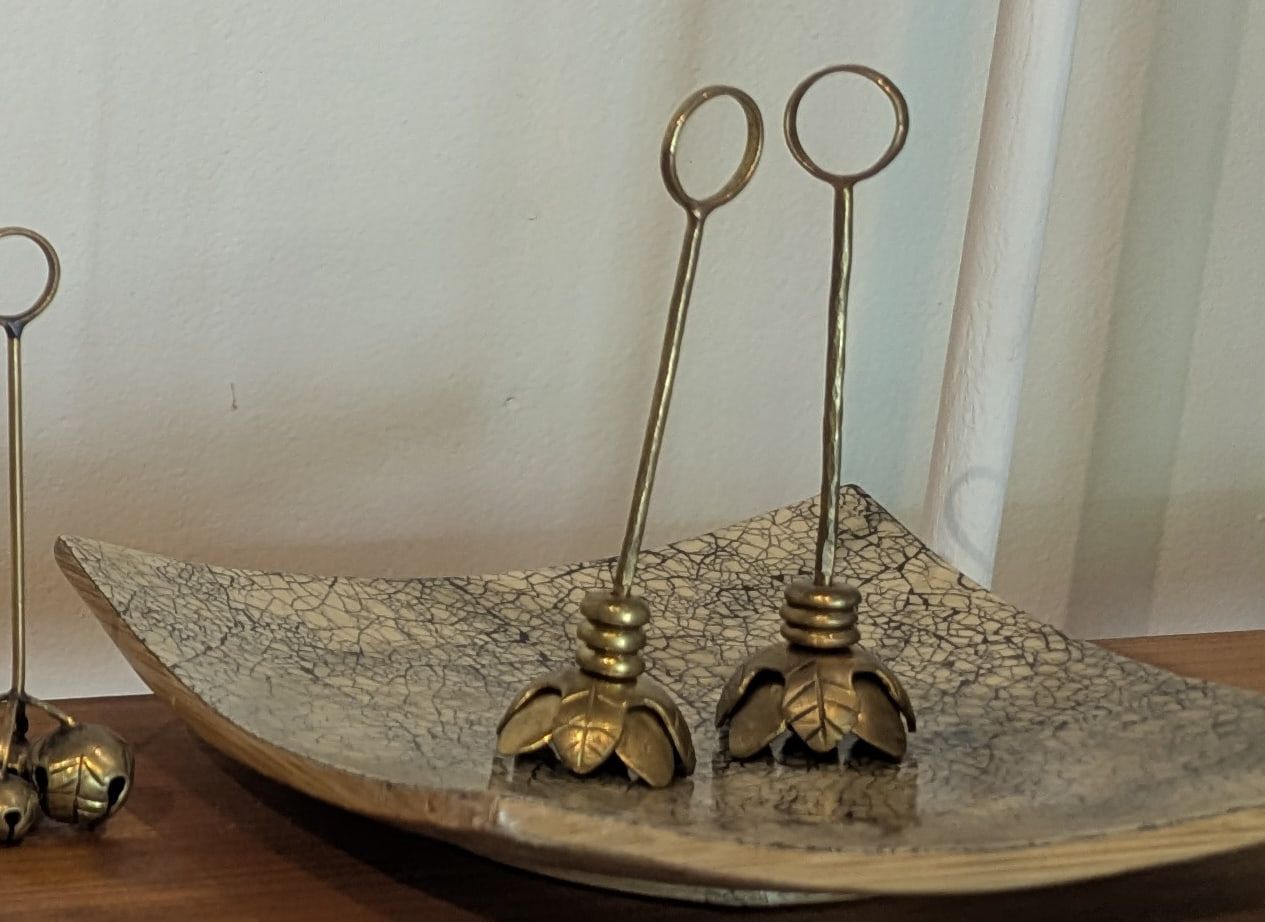 Two tall brass stems with loops at the top and open lotus flowers at the base, standing on a crackle-glaze tray