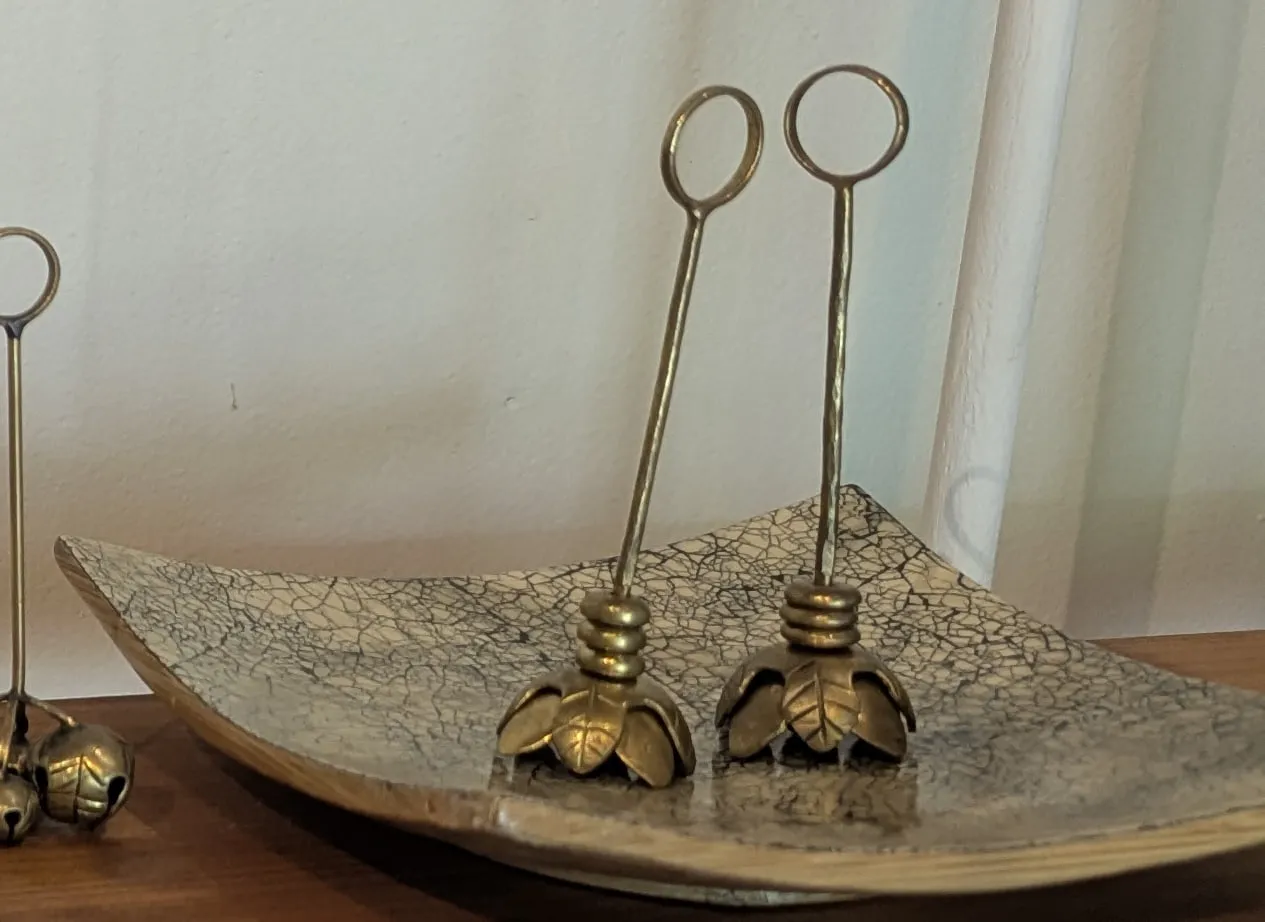 Two tall brass stems with loops at the top and open lotus flowers at the base, standing on a crackle-glaze tray