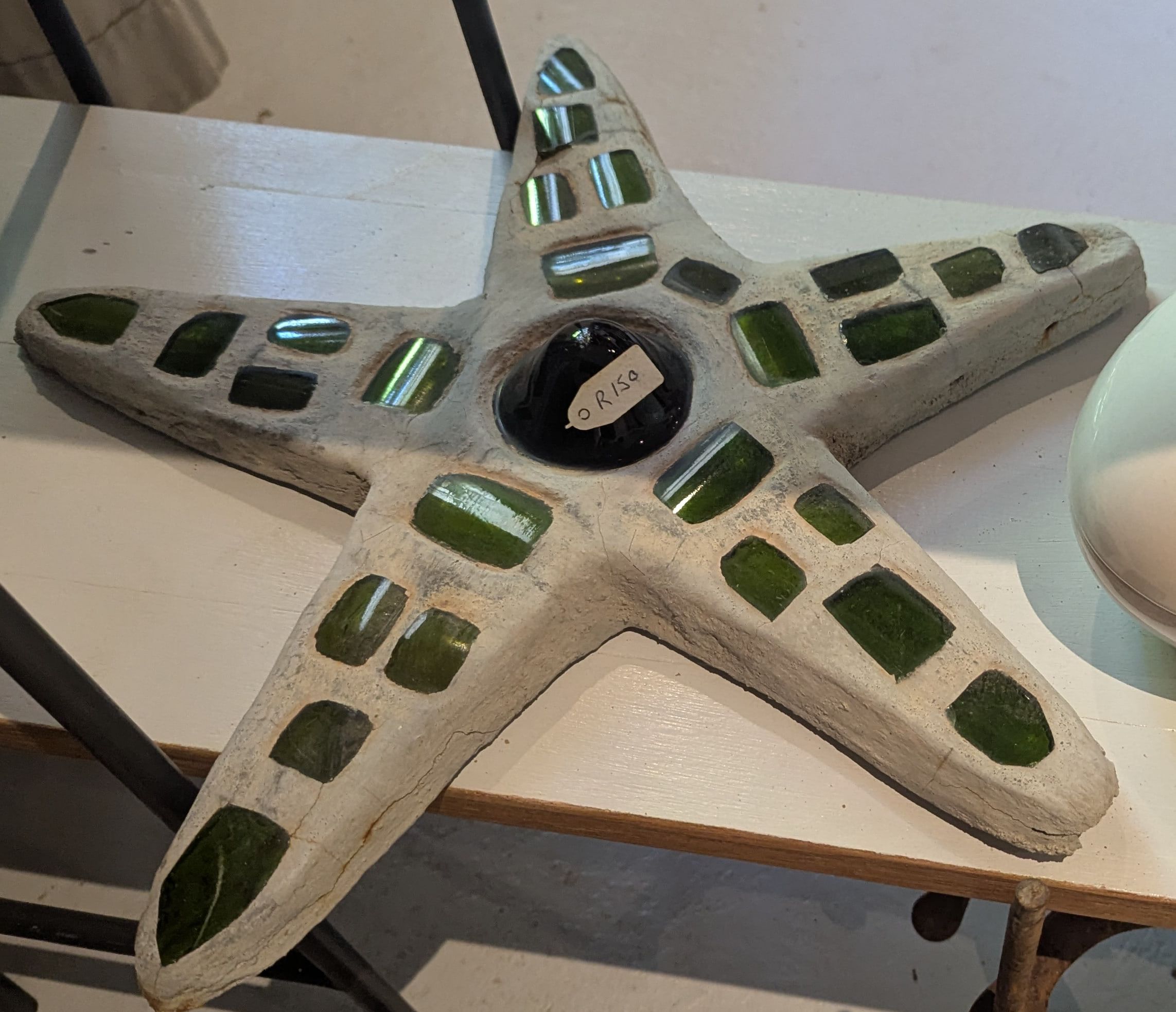 A cast concrete starfish set with pieces of green bottle glass