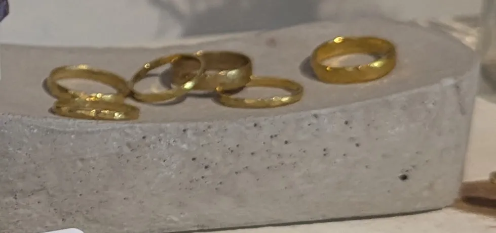 Several slim brass rings on a cast concrete dish