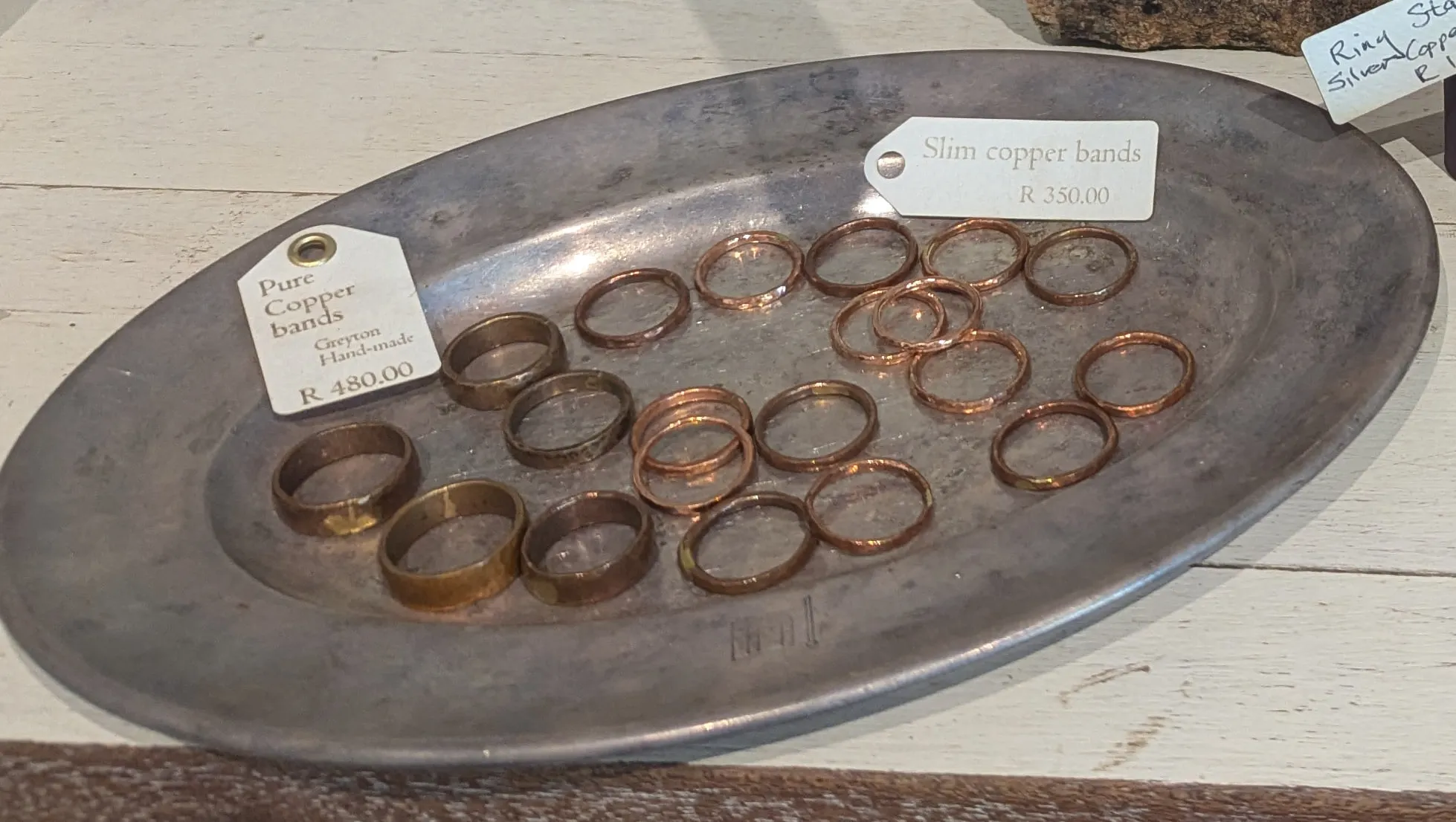 A pewter platter scattered with plain copper rings in two widths