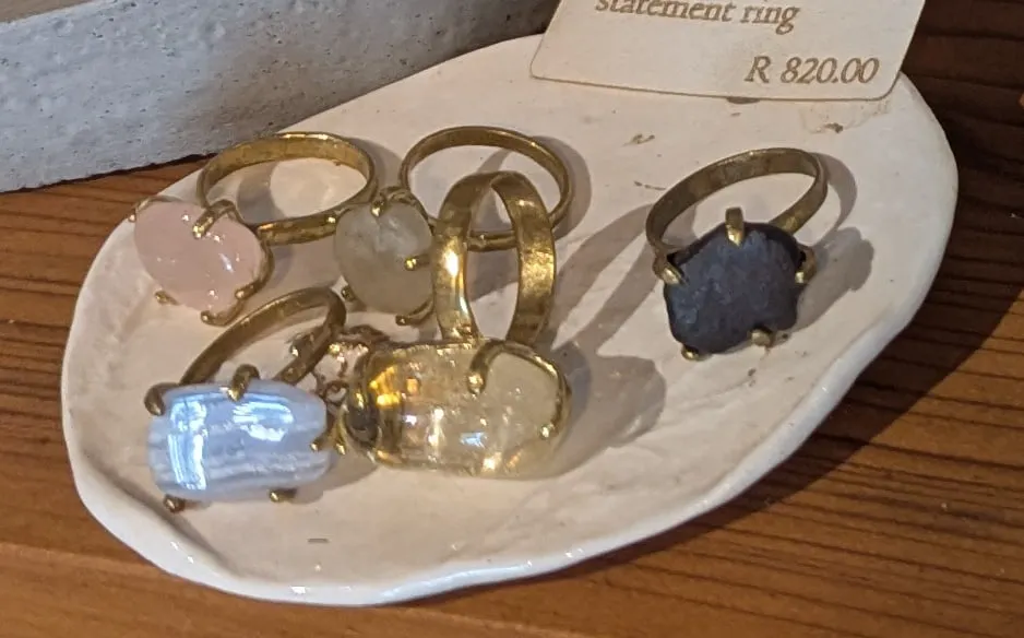 Brass rings set with pink, clear and dark crystals on a white ceramic dish