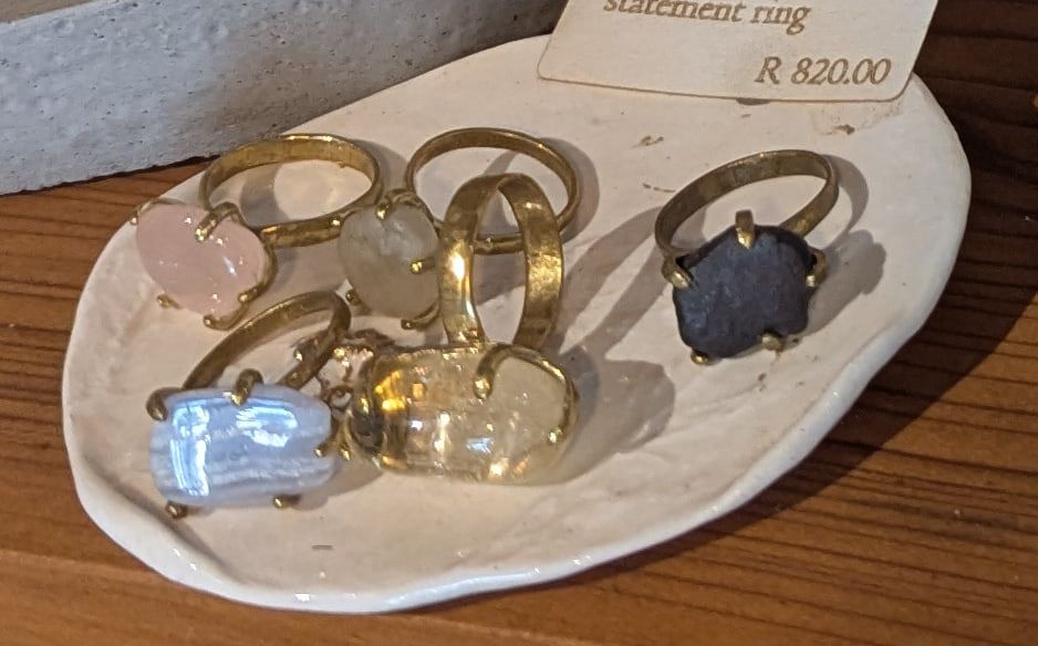 Brass rings set with pink, clear and dark crystals on a white ceramic dish