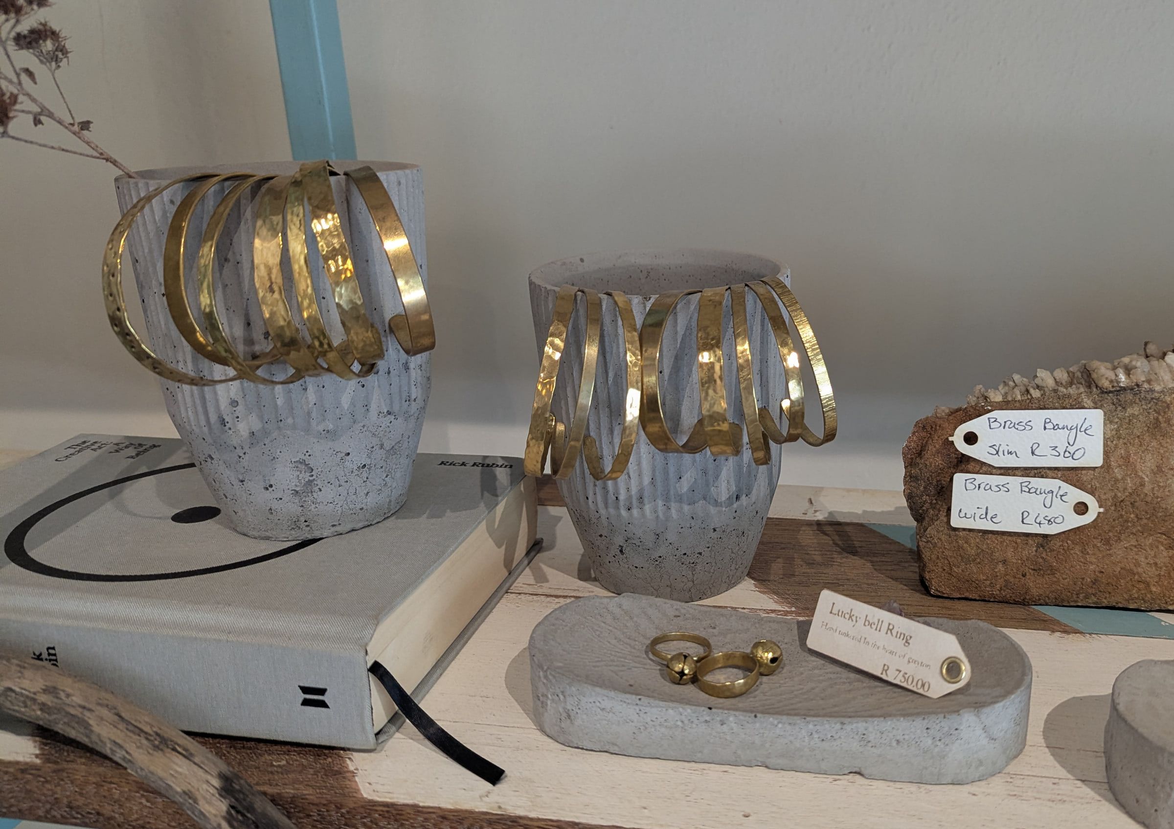 Hammered brass cuffs on fluted concrete pots beside a lucky bell ring