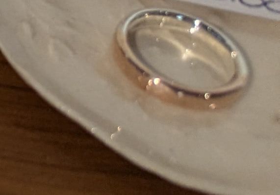 A ring in rose-coloured copper alloy and white silver on a ceramic dish