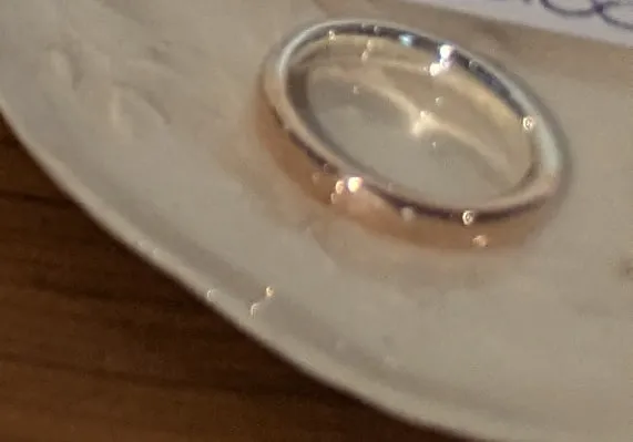 A ring in rose-coloured copper alloy and white silver on a ceramic dish