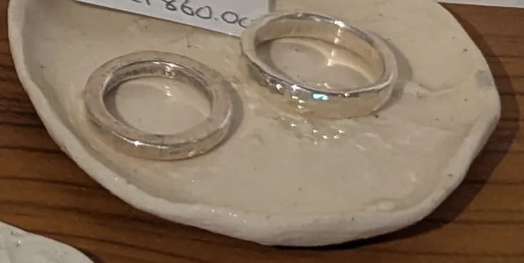 Two fine silver bands on a white ceramic dish