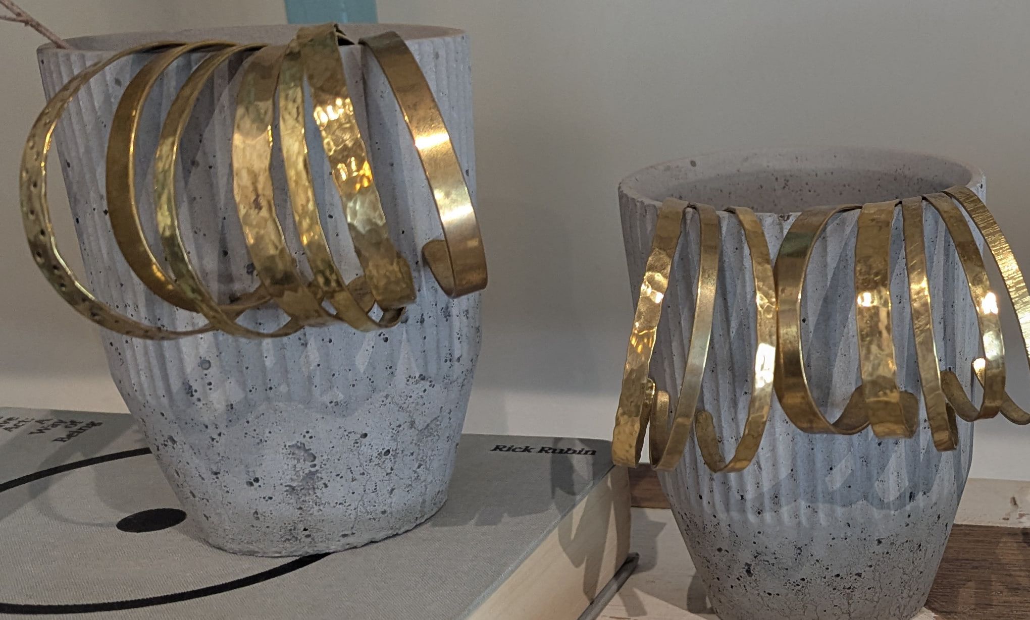 Hammered brass cuffs hung over two fluted concrete pots
