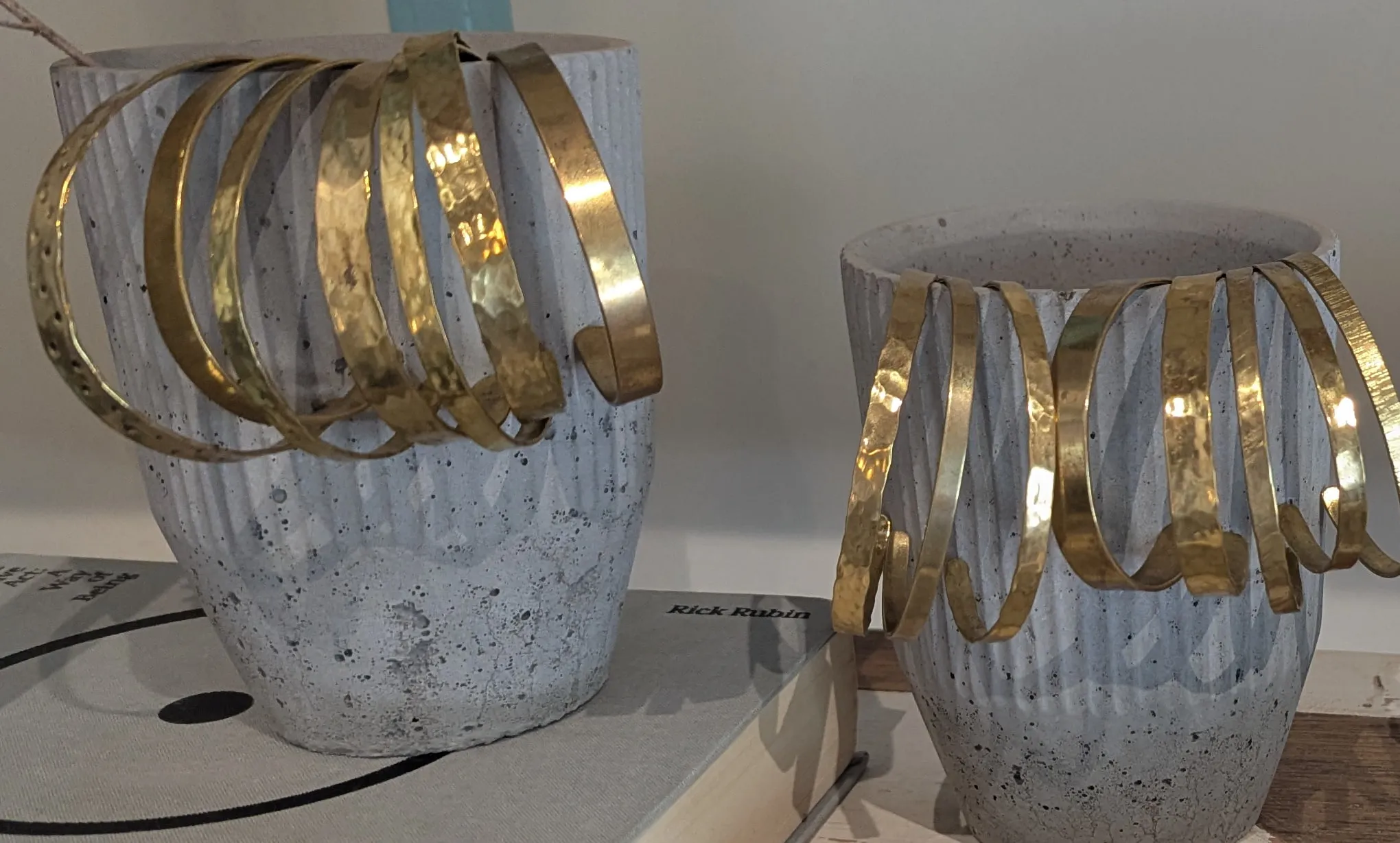 Hammered brass cuffs hung over two fluted concrete pots