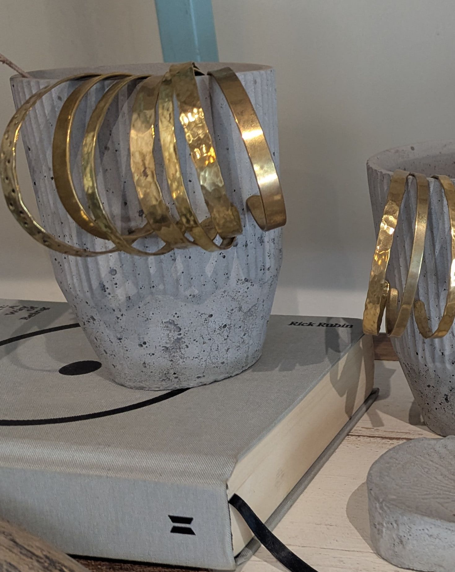 Hammered brass cuffs hung over a fluted concrete pot