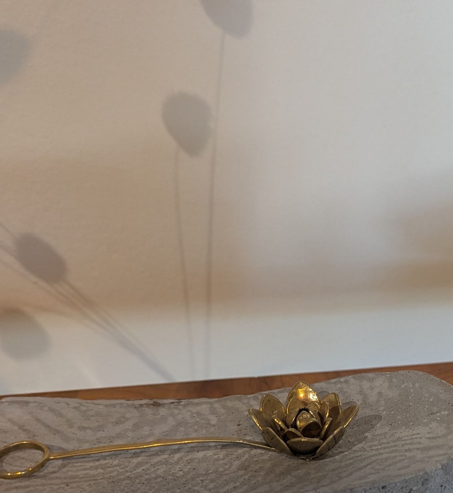 A brass lotus with layered petals resting on a concrete plinth