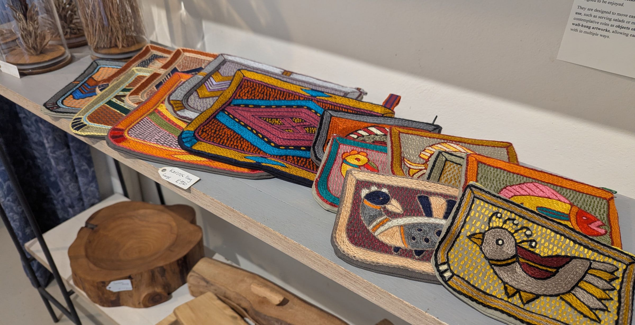 Hand-embroidered Kaross bags laid out on a shelf