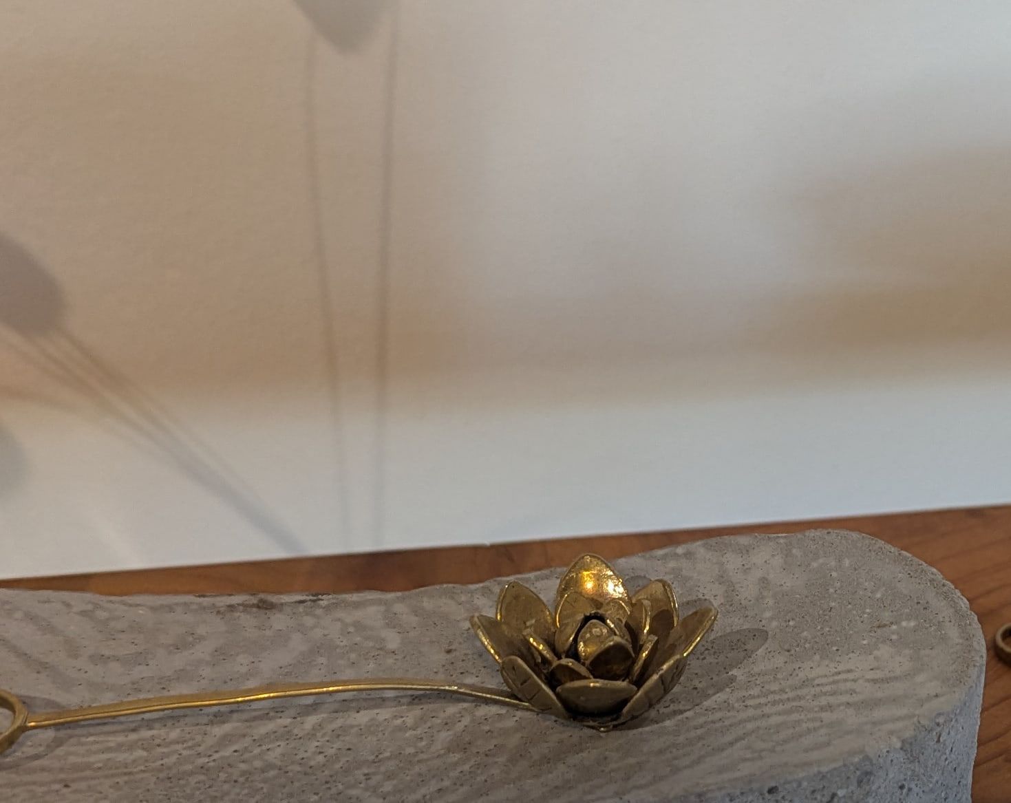 The Thousand Petal Lotus: a brass flower with layered petals on a curved stem, resting on a concrete plinth