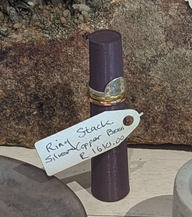 A stack of silver, copper and brass rings on a dark ring stand