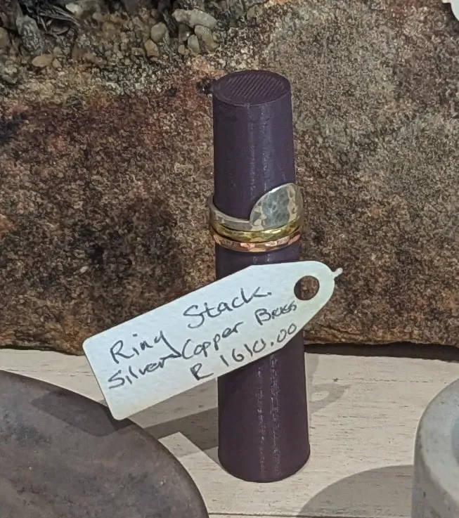A stack of silver, copper and brass rings on a dark ring stand