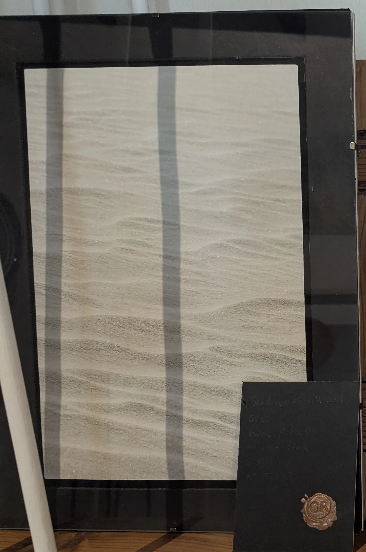 A framed photograph of fine sand ripples in a black frame