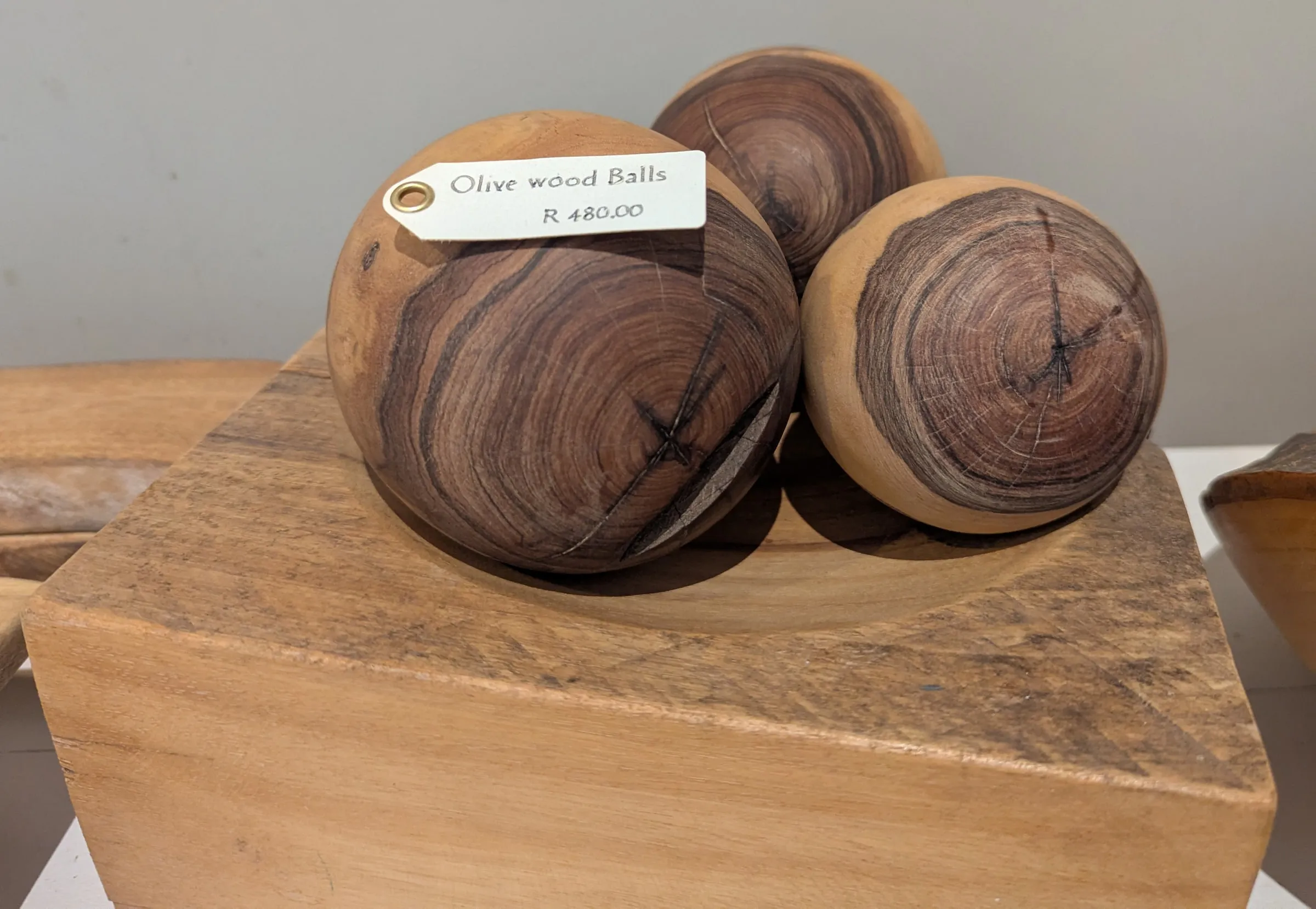 Three olive wood spheres with dark swirling grain resting in a carved wooden block