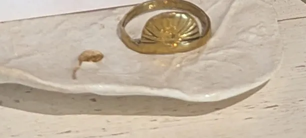 A brass ring with a half-sun motif on a white ceramic dish