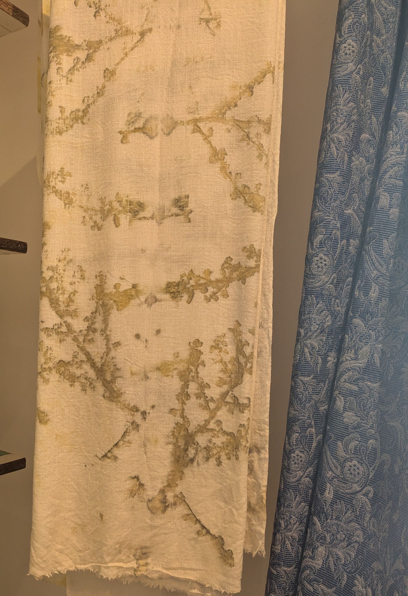 A leaf-printed cashmere scarf beside a damask curtain