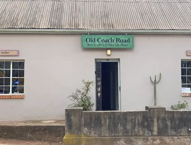 The front of Old Coach Road: a white wall, a green sign over the open door and white sash windows