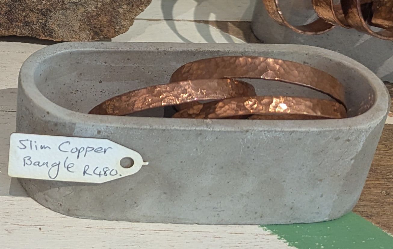 Slim hammered copper bangles in a cast concrete dish