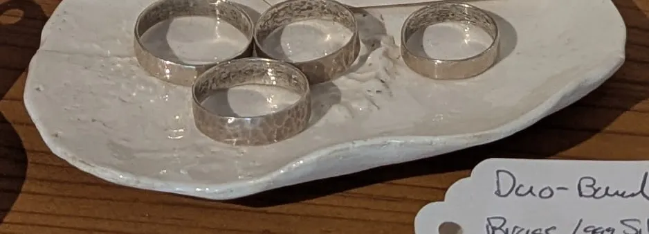 Hammered sterling silver bands on a white ceramic dish