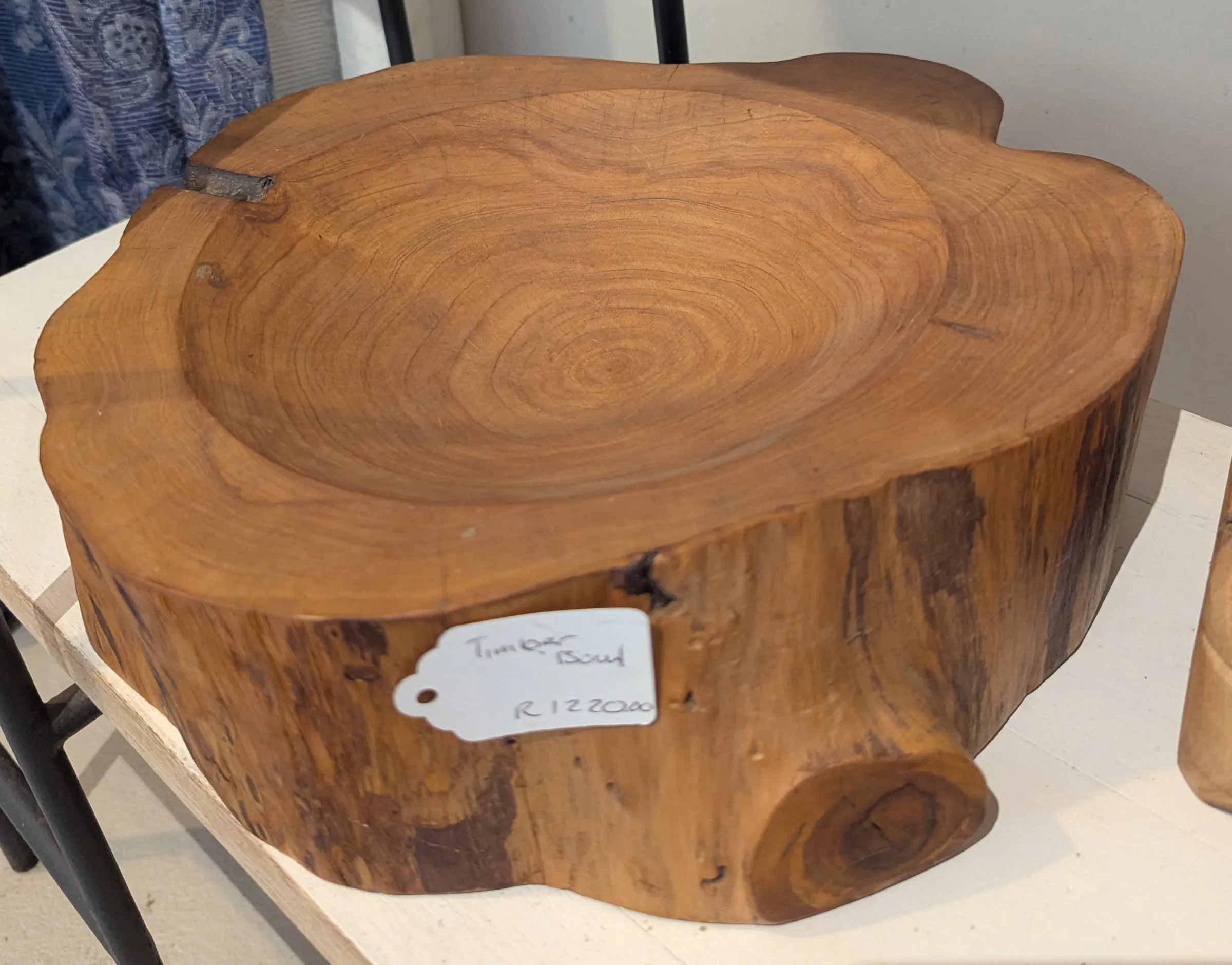 A wide shallow bowl carved into a thick slice of tree trunk with visible growth rings