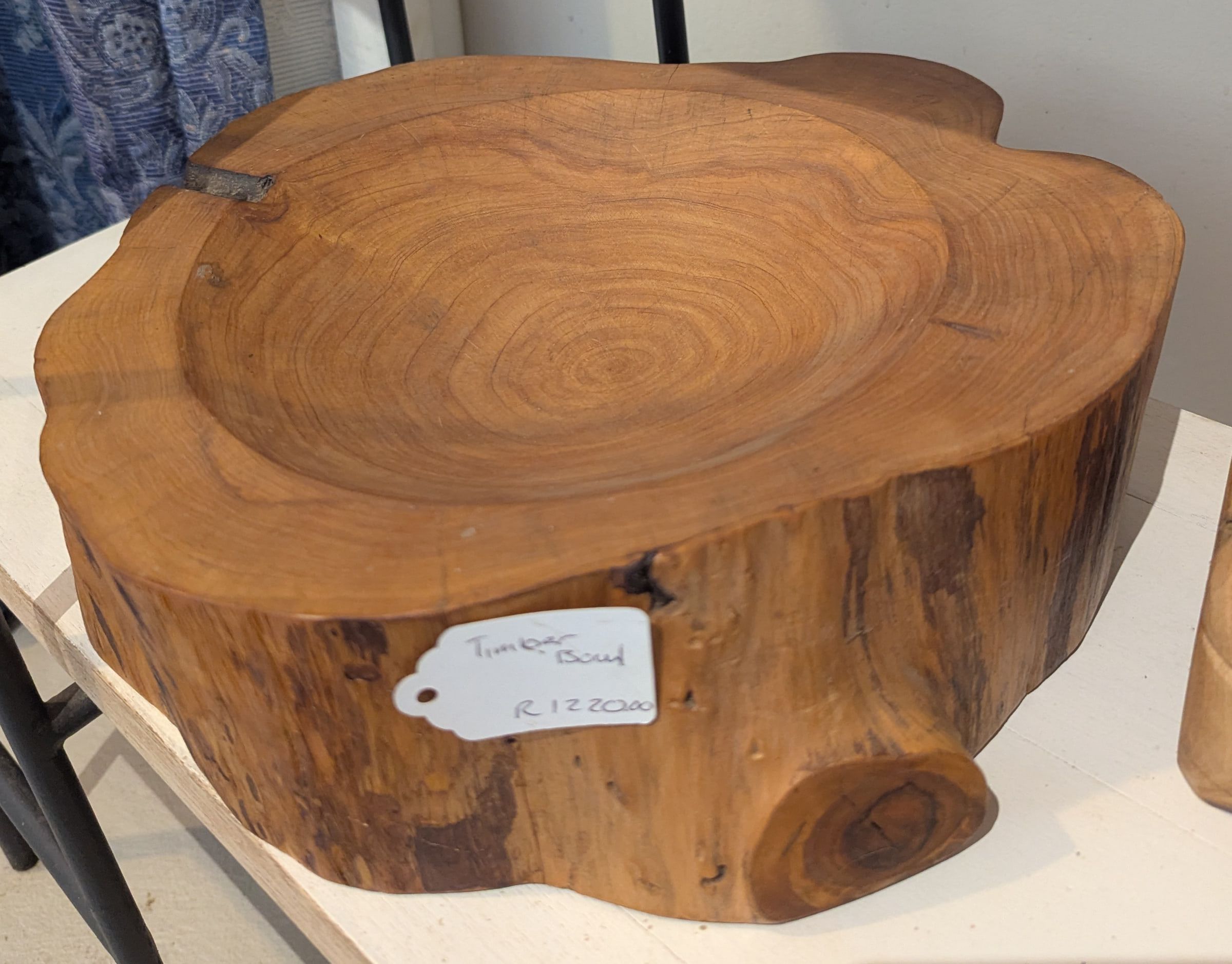 A wide shallow bowl carved into a thick slice of tree trunk with visible growth rings