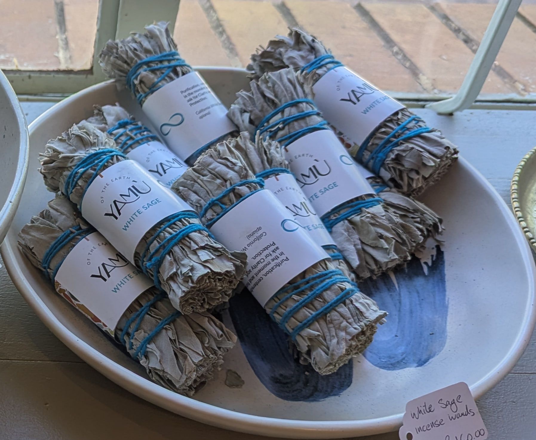 White sage incense wands tied with blue thread in a white bowl