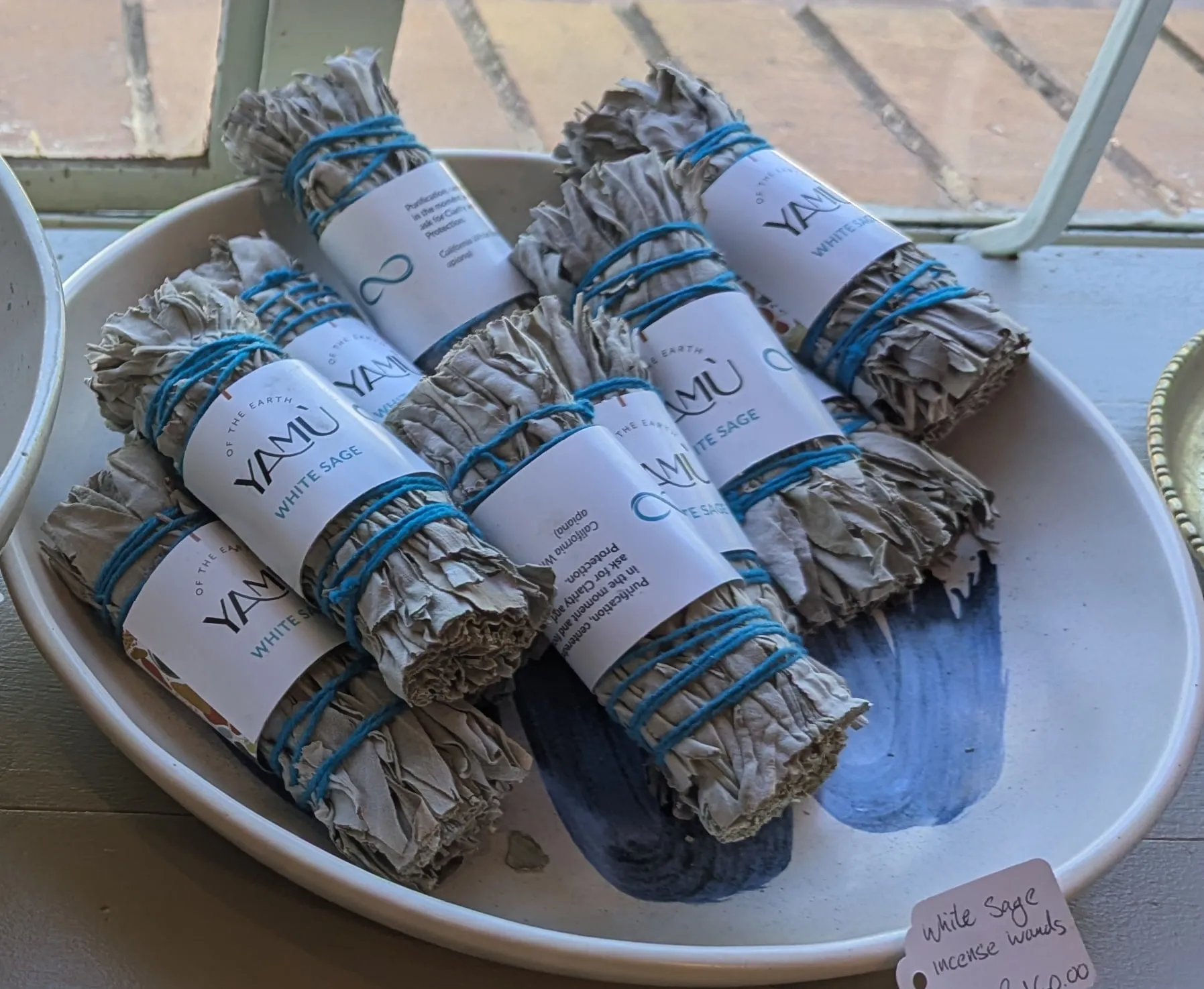 White sage incense wands tied with blue thread in a white bowl