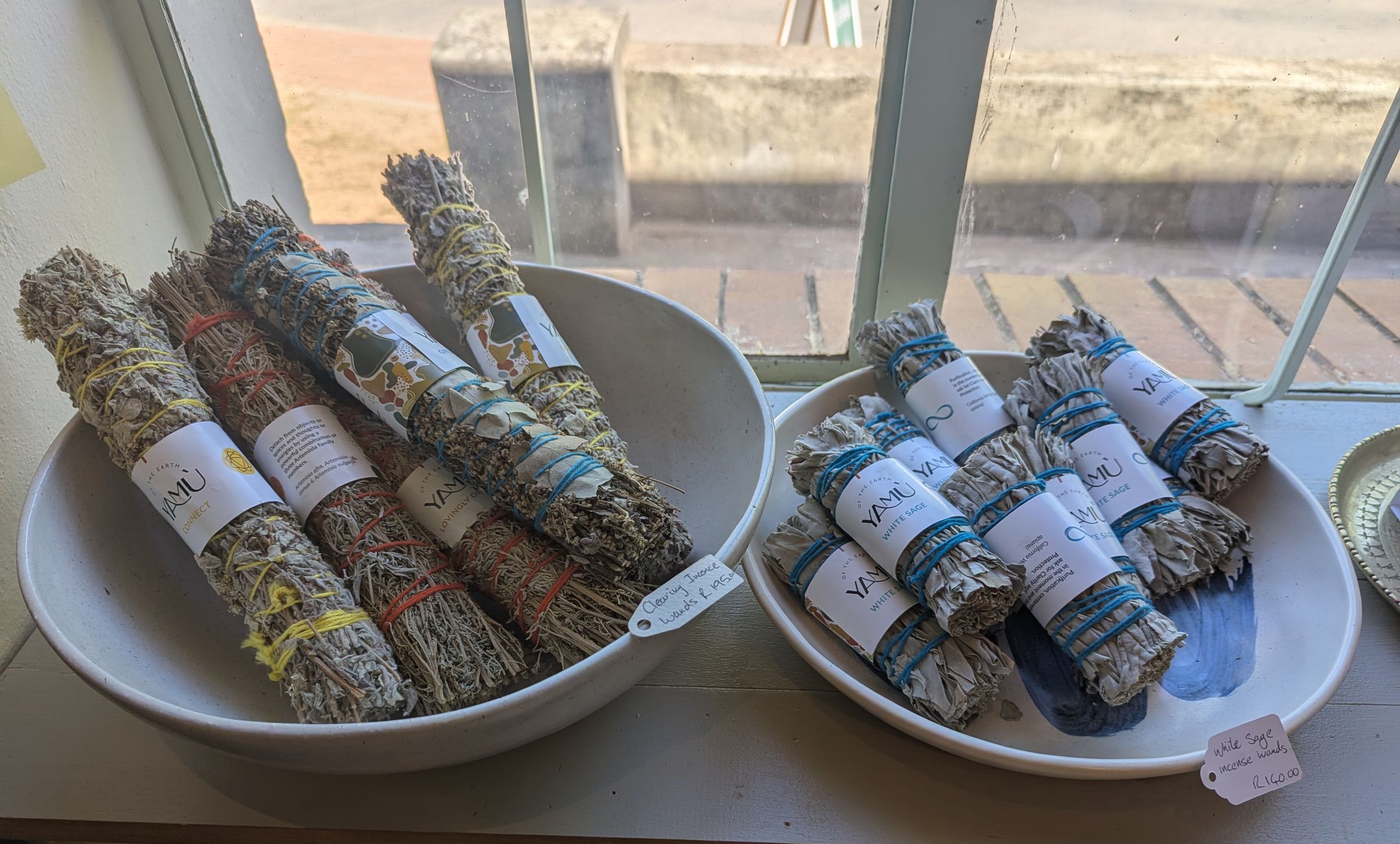 Herb bundles in white bowls on the sunny window sill, with DS Botha Street outside